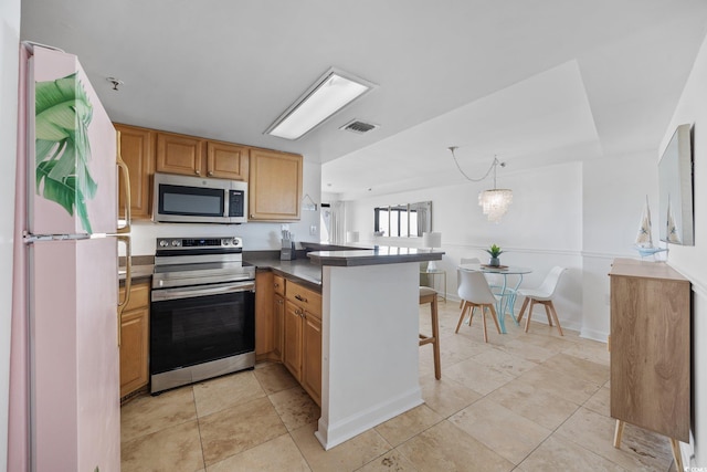 5511 N Ocean Blvd Unit 310, Myrtle Beach, SC 29577 - kitchen featuring stainless steel appliances, a peninsula, a kitchen breakfast bar, dark countertops, and light tile patterned floors