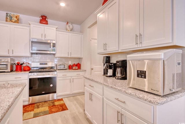160 Juniata Loop, Little River, SC 29566 - kitchen with stainless steel appliances, white cabinets, tasteful backsplash, and light wood-style flooring