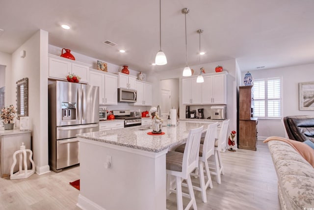160 Juniata Loop, Little River, SC 29566 - kitchen featuring appliances with stainless steel finishes, light wood finished floors, a breakfast bar, white cabinets, and an island with sink
