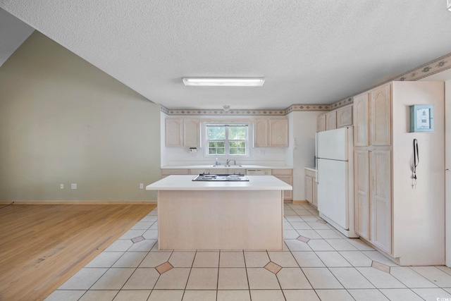7288 Schooners Ct SW, Ocean Isle Beach, NC 28469 - kitchen featuring white appliances, a textured ceiling, light countertops, a kitchen island, and light brown cabinets