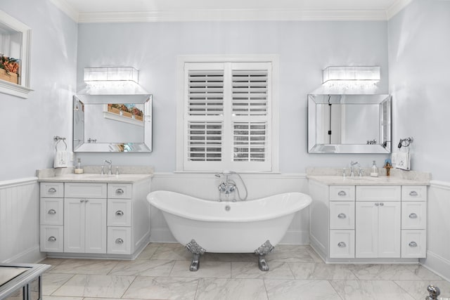 155 Preservation Cir, Pawleys Island, SC 29585 - bathroom with marble look tiles, ornamental molding, two vanities, a soaking tub, and a wainscoted wall