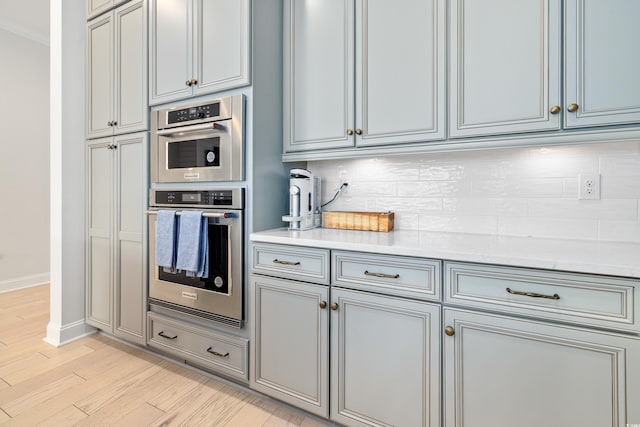 6304 Chadderton Cir, Myrtle Beach, SC 29579 - kitchen featuring stainless steel double oven, backsplash, light wood-style floors, and light stone countertops