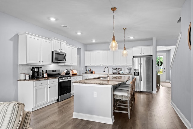 215 Kendrick St, Little River, SC 29566 - kitchen with appliances with stainless steel finishes, dark stone countertops, white cabinetry, a kitchen island with sink, and recessed lighting