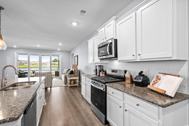 215 Kendrick St, Little River, SC 29566 - kitchen with stainless steel appliances, open floor plan, white cabinetry, wood finished floors, and dark stone countertops