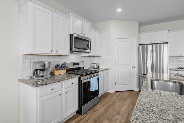 2106 Ainsley Dr, Little River, SC 29566 - kitchen with appliances with stainless steel finishes, decorative backsplash, wood finished floors, white cabinetry, and recessed lighting