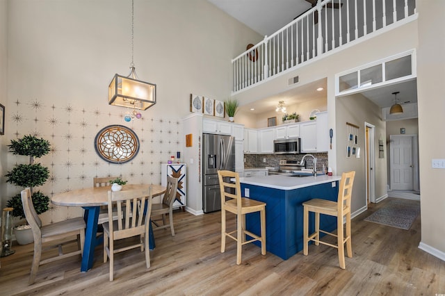 1984 Green Fern Ln Unit 1984, Myrtle Beach, SC 29579 - kitchen with stainless steel appliances, light wood-style flooring, a peninsula, a breakfast bar, and a towering ceiling