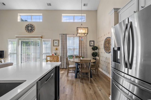 1984 Green Fern Ln Unit 1984, Myrtle Beach, SC 29579 - kitchen featuring appliances with stainless steel finishes, light wood-style flooring, hanging light fixtures, white cabinetry, and a towering ceiling