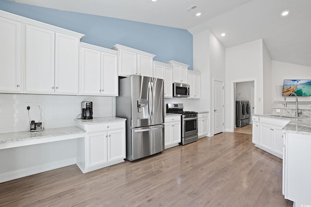 865 Summer Starling Pl, Myrtle Beach, SC 29577 - kitchen with stainless steel appliances, washing machine and dryer, decorative backsplash, high vaulted ceiling, and white cabinets