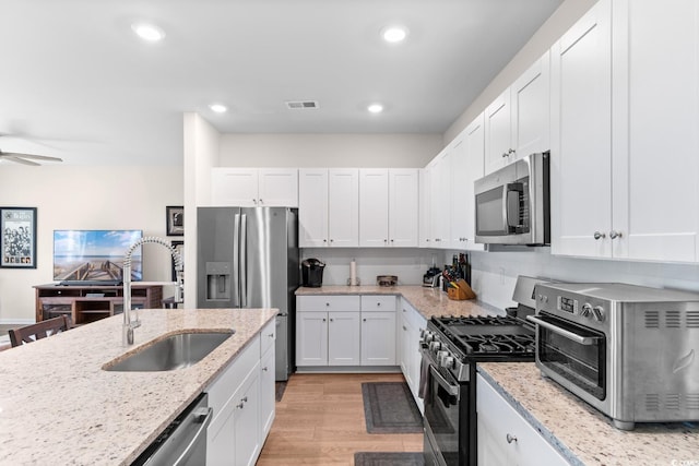 1029 Saltgrass Way, Myrtle Beach, SC 29588 - kitchen with stainless steel appliances, white cabinets, light wood-type flooring, light stone counters, and recessed lighting