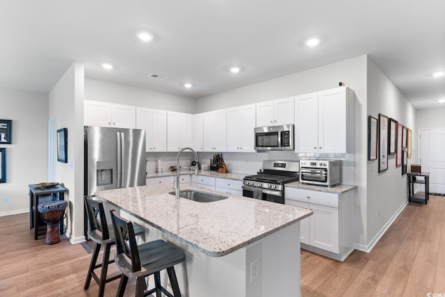 1029 Saltgrass Way, Myrtle Beach, SC 29588 - kitchen featuring stainless steel appliances, a kitchen breakfast bar, light stone counters, a center island with sink, and recessed lighting
