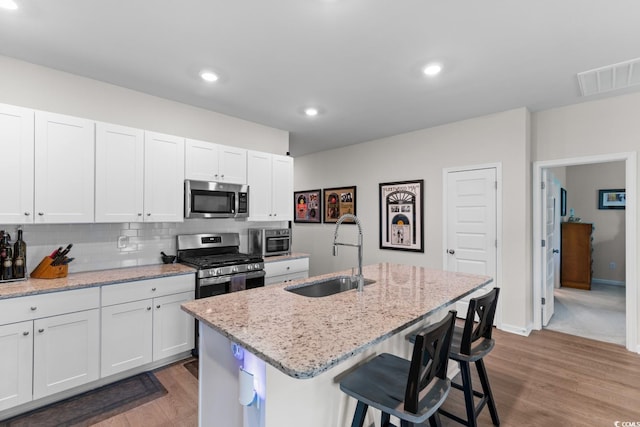 1029 Saltgrass Way, Myrtle Beach, SC 29588 - kitchen with stainless steel appliances, wood finished floors, white cabinetry, a kitchen bar, and recessed lighting