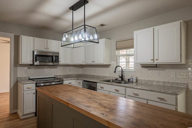 1897 Mossberg Dr, Sumter, SC 29150 - kitchen featuring butcher block countertops, stainless steel appliances, backsplash, white cabinetry, and a textured ceiling
