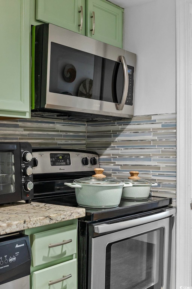 2001 S Ocean Blvd Unit 1405, Myrtle Beach, SC 29577 - kitchen view of stainless steel appliances, backsplash, green cabinetry, and light stone counters