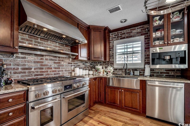 1473 Basin Trl, Murrells Inlet, SC 29576 - kitchen with appliances with stainless steel finishes, exhaust hood, light stone countertops, light wood-type flooring, and glass insert cabinets