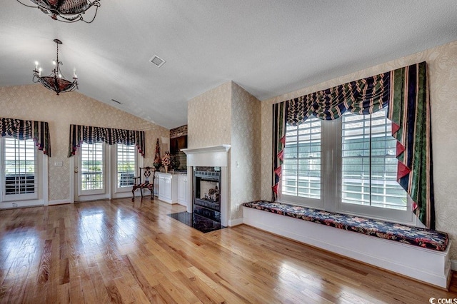 1473 Basin Trl, Murrells Inlet, SC 29576 - unfurnished living room featuring a chandelier, wallpapered walls, wood finished floors, vaulted ceiling, and a fireplace with flush hearth