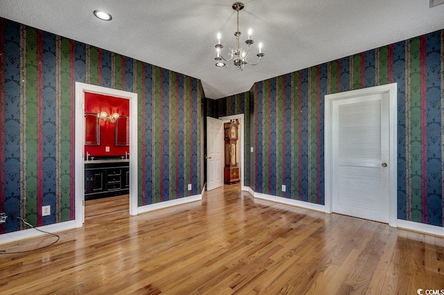 1473 Basin Trl, Murrells Inlet, SC 29576 - unfurnished room with wood finished floors, a chandelier, wallpapered walls, and a textured ceiling
