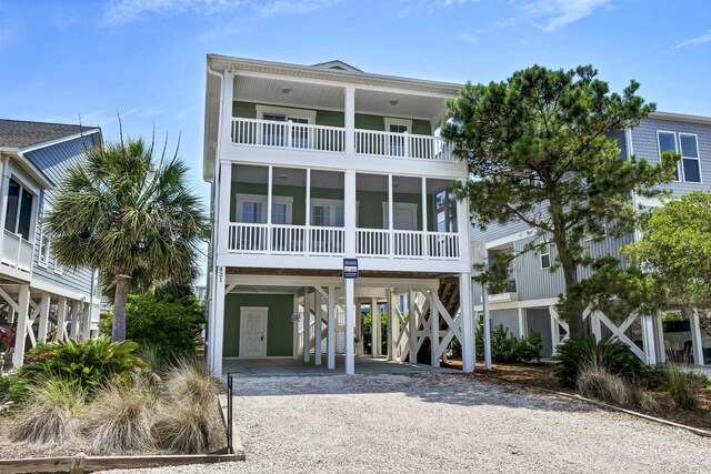 421 30th Ave S, Sunset Beach, NC 28468 - coastal home with a carport, a balcony, gravel driveway, and a sunroom