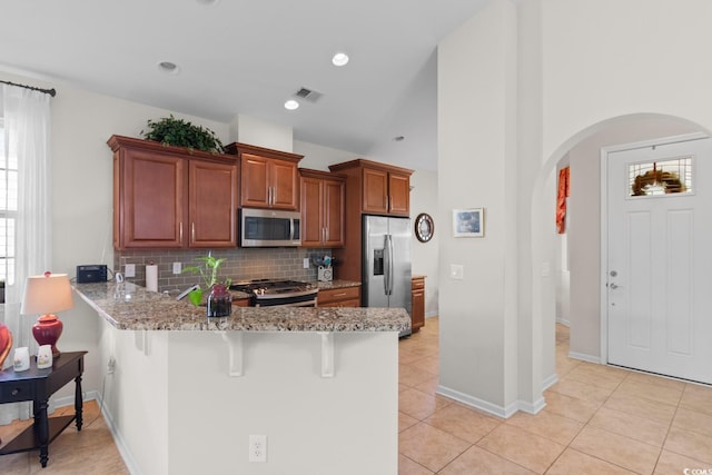 637 Grand Cypress Way, Murrells Inlet, SC 29576 - kitchen with appliances with stainless steel finishes, arched walkways, a peninsula, light stone countertops, and decorative backsplash