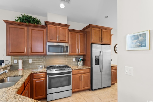 637 Grand Cypress Way, Murrells Inlet, SC 29576 - kitchen with appliances with stainless steel finishes, decorative backsplash, light stone countertops, light tile patterned floors, and brown cabinets