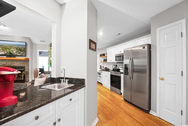 174 Edward Ave, Murrells Inlet, SC 29576 - kitchen featuring appliances with stainless steel finishes, white cabinetry, light wood finished floors, a fireplace, and recessed lighting