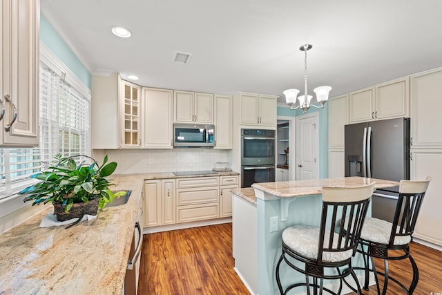 1032 Chelsey Cir, Conway, SC 29526 - kitchen featuring appliances with stainless steel finishes, wood finished floors, a kitchen bar, light stone counters, and a chandelier