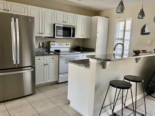 4840 Moss Creek Loop Unit 31, Murrells Inlet, SC 29576 - kitchen featuring stainless steel appliances, a kitchen breakfast bar, white cabinetry, light tile patterned floors, and a textured ceiling