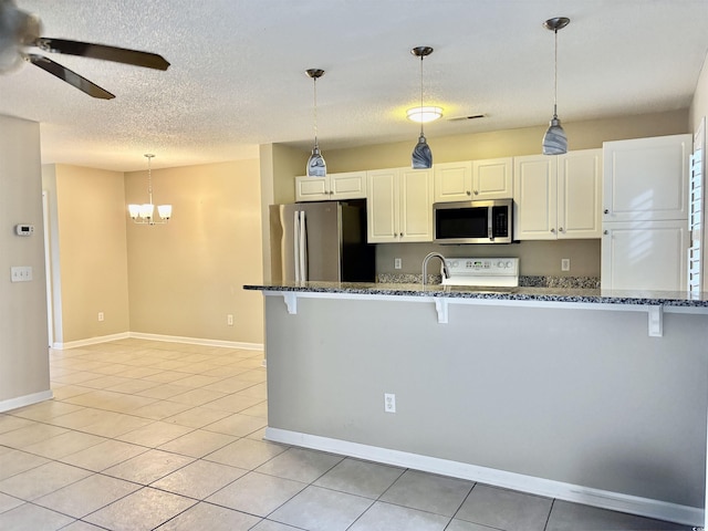 4840 Moss Creek Loop Unit 31, Murrells Inlet, SC 29576 - kitchen featuring appliances with stainless steel finishes, a breakfast bar, a ceiling fan, dark stone counters, and a textured ceiling