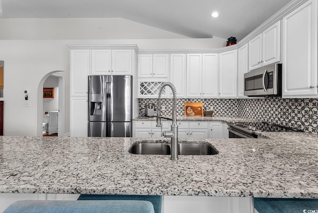 5 Tiara Ln, Murrells Inlet, SC 29576 - kitchen featuring stainless steel appliances, lofted ceiling, light stone counters, arched walkways, and backsplash