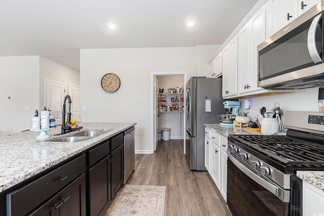 651 Choctaw Dr, Conway, SC 29526 - kitchen featuring appliances with stainless steel finishes, white cabinetry, light wood-style floors, light stone countertops, and dark cabinetry