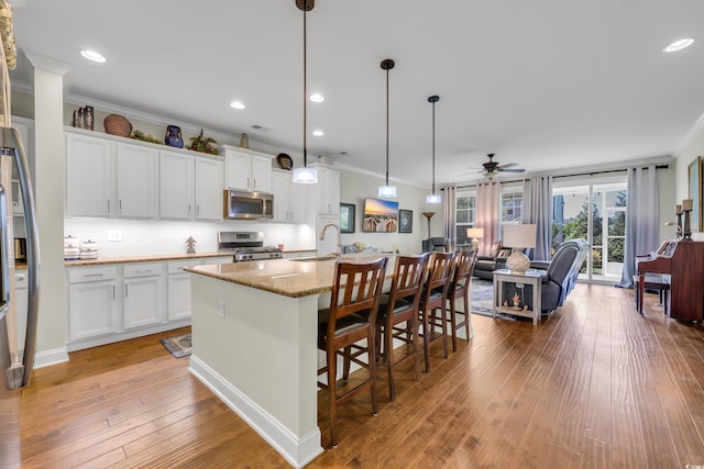 2685 Scarecrow Way, Myrtle Beach, SC 29579 - kitchen with stainless steel appliances, crown molding, light wood-style flooring, light stone counters, and white cabinetry