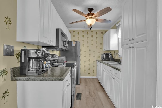 6001-1459 S Kings Hwy, Myrtle Beach, SC 29575 - kitchen featuring appliances with stainless steel finishes, dark countertops, light wood finished floors, ceiling fan, and wallpapered walls