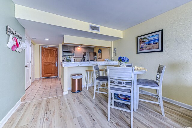 9550 Shore Dr Unit 225, Myrtle Beach, SC 29572 - kitchen with stainless steel appliances, a kitchen bar, light wood-style floors, and a peninsula