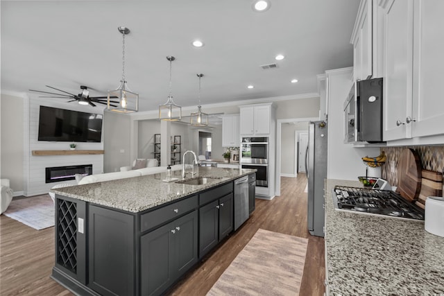 264 Switchgrass Loop, Little River, SC 29566 - kitchen with white cabinets, appliances with stainless steel finishes, a ceiling fan, a kitchen island with sink, and ornamental molding