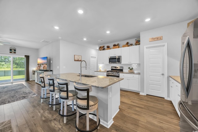 788 Dusty Pine Way, Myrtle Beach, SC 29588 - kitchen featuring stainless steel appliances, dark wood-type flooring, light stone counters, a center island with sink, and a kitchen bar