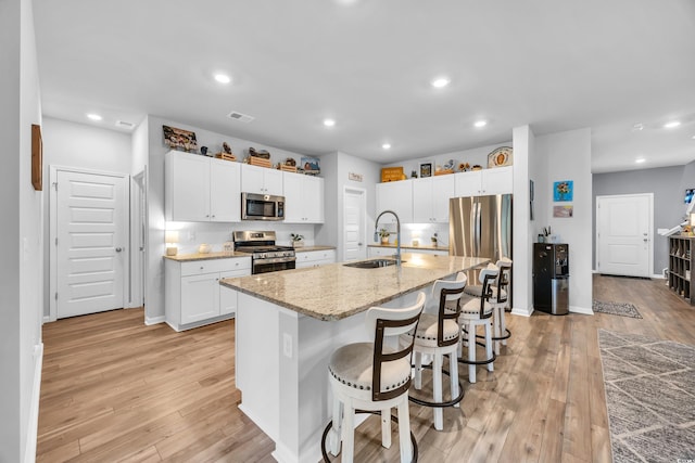 788 Dusty Pine Way, Myrtle Beach, SC 29588 - kitchen with stainless steel appliances, light wood-style floors, light stone countertops, white cabinetry, and a kitchen bar