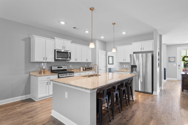 226 Calhoun Falls Dr, Myrtle Beach, SC 29579 - kitchen featuring appliances with stainless steel finishes, light wood-type flooring, a breakfast bar, a center island with sink, and white cabinets