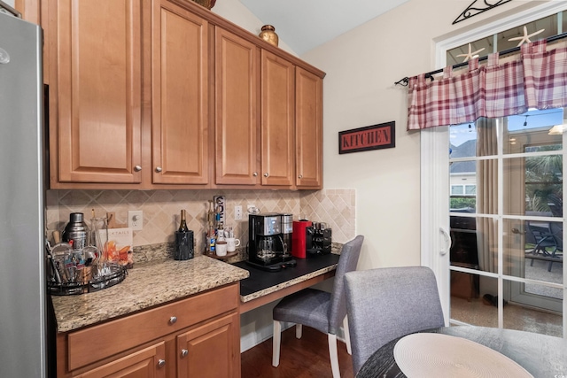 908 Ashbourn Ct, Murrells Inlet, SC 29576 - kitchen featuring tasteful backsplash, light stone countertops, brown cabinetry, built in desk, and freestanding refrigerator