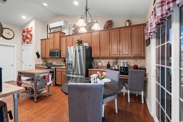 908 Ashbourn Ct, Murrells Inlet, SC 29576 - kitchen featuring appliances with stainless steel finishes, a wall unit AC, decorative backsplash, light wood-style floors, and high vaulted ceiling