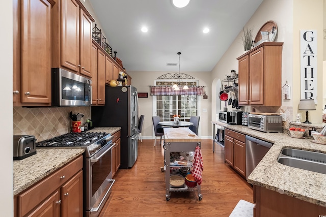 908 Ashbourn Ct, Murrells Inlet, SC 29576 - kitchen featuring stainless steel appliances, arched walkways, tasteful backsplash, light wood finished floors, and light stone countertops