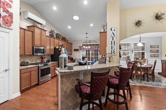 908 Ashbourn Ct, Murrells Inlet, SC 29576 - kitchen featuring stainless steel appliances, light wood-type flooring, a kitchen bar, brown cabinetry, and a wall mounted AC