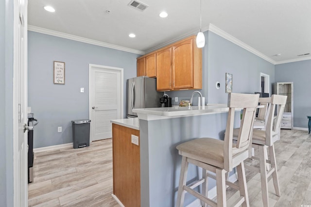 314 Black Oak Ln Unit 102, Murrells Inlet, SC 29576 - kitchen featuring freestanding refrigerator, crown molding, light wood-style flooring, a kitchen breakfast bar, and a peninsula