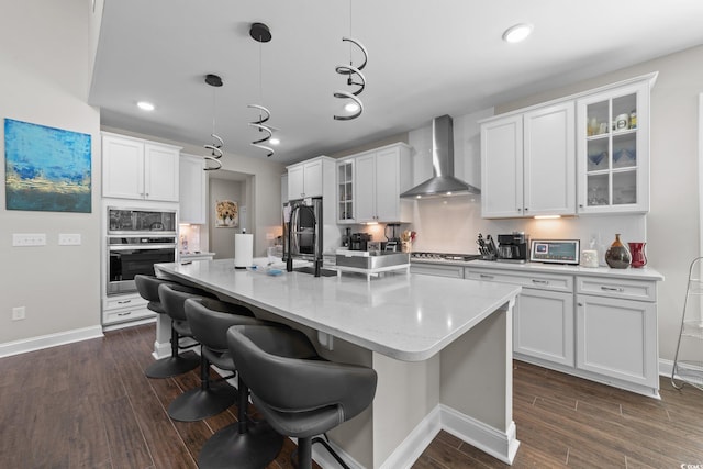 2212 Leeboard Ct, Myrtle Beach, SC 29579 - kitchen featuring stainless steel oven, wall chimney exhaust hood, dark wood-type flooring, white cabinets, and a breakfast bar