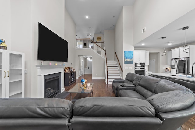 2212 Leeboard Ct, Myrtle Beach, SC 29579 - living area featuring a towering ceiling, stairs, dark wood-style flooring, a fireplace, and recessed lighting