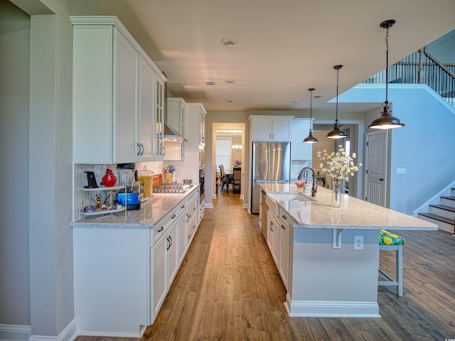 376 Mikita Dr, Surfside Beach, SC 29575 - kitchen featuring wood finished floors, stainless steel appliances, a kitchen bar, white cabinets, and backsplash