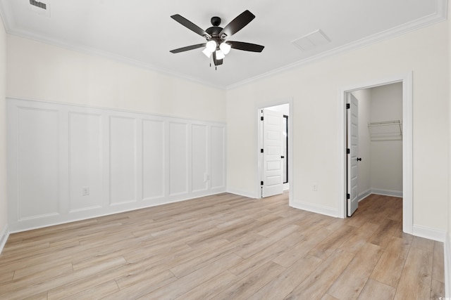 2428 Park St, North Myrtle Beach, SC 29582 - unfurnished bedroom with light wood-style floors, crown molding, a spacious closet, a decorative wall, and a ceiling fan