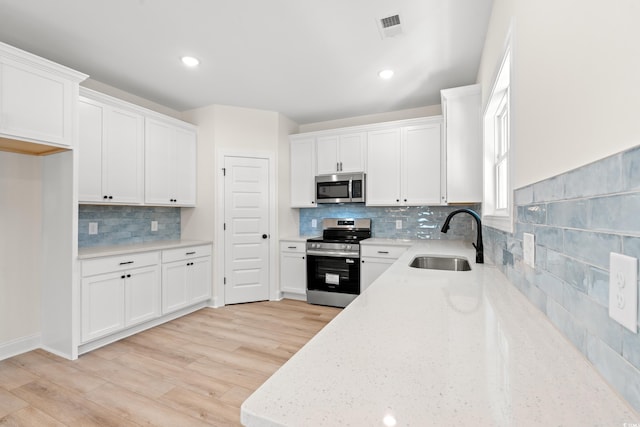 2426 Park St, North Myrtle Beach, SC 29582 - kitchen with stainless steel appliances, backsplash, light stone counters, white cabinetry, and recessed lighting