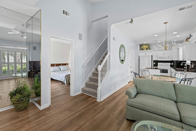 503 20th Ave N Unit 9D, North Myrtle Beach, SC 29582 - living room with stairs, a ceiling fan, dark wood-style floors, a high ceiling, and a chandelier