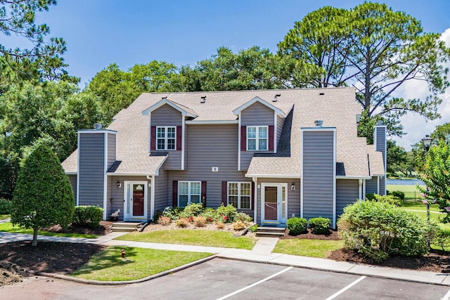 503 20th Ave N Unit 9D, North Myrtle Beach, SC 29582 - view of front of house featuring a chimney, uncovered parking, roof with shingles, and a front lawn