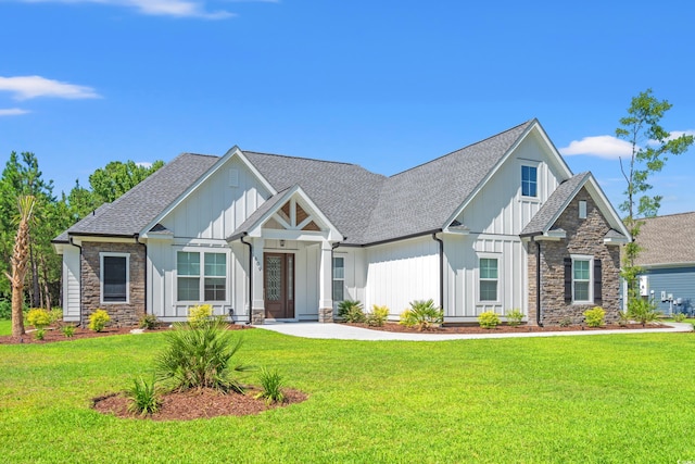 609 Mccown Dr, Conway, SC 29526 - view of front of home featuring stone siding, a front yard, a shingled roof, and board and batten siding