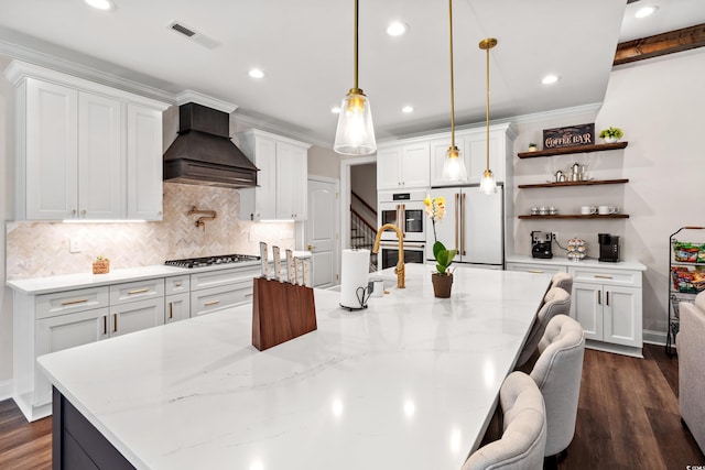 609 Mccown Dr, Conway, SC 29526 - kitchen featuring custom exhaust hood, white appliances, a large island with sink, open shelves, and decorative backsplash